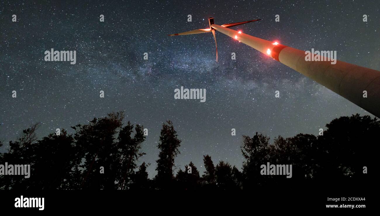 Turbina eolica industriale in mezzo alla foresta, nightshot con strada lattea e cielo stellato. Inversione di tendenza dell'energia di sostenibilità. Foto Stock