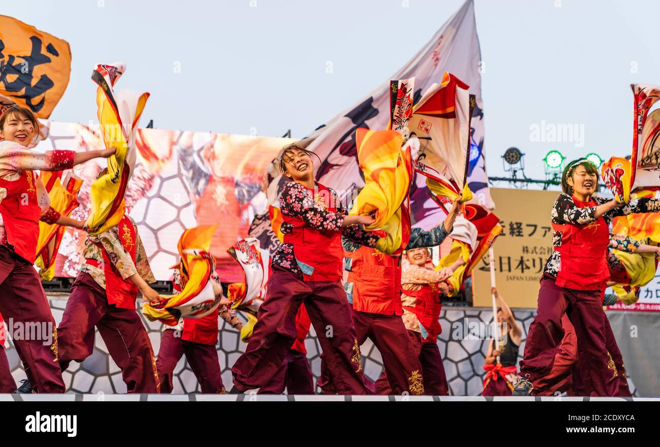 Una squadra giapponese di ballerine di donne yosakoi sul palco che girano i vestiti gialli mentre ballano durante il festival Kyusyu Gassai a Kumamoto in Giappone. Foto Stock