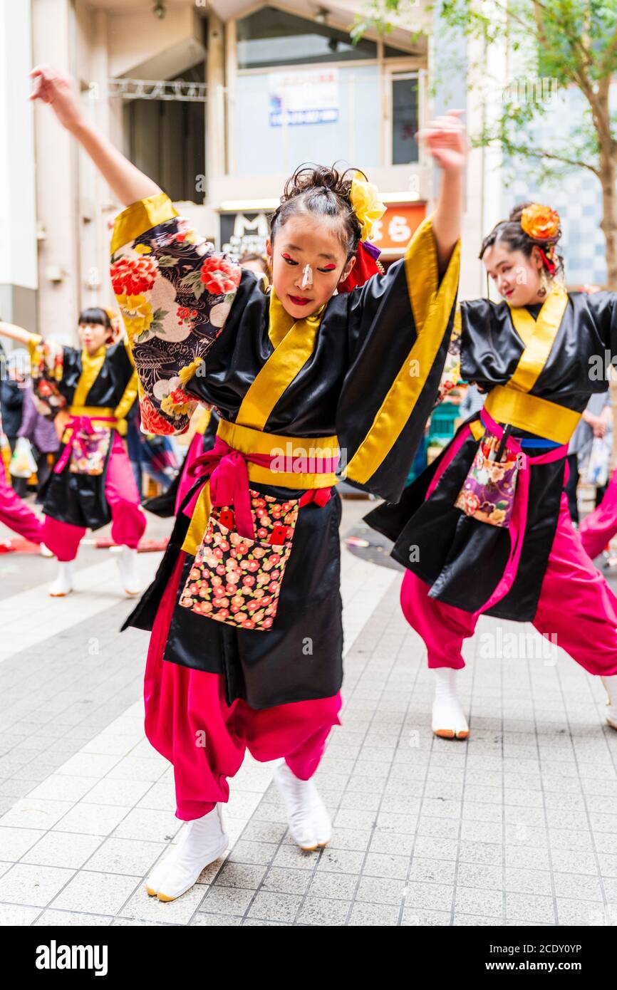 Primo piano della squadra giapponese di ballerini yosakoi che ballano con una giovane ballerina di fronte alla spettatrice, al festival Kyusyu Gassai, Kumamoto. Foto Stock
