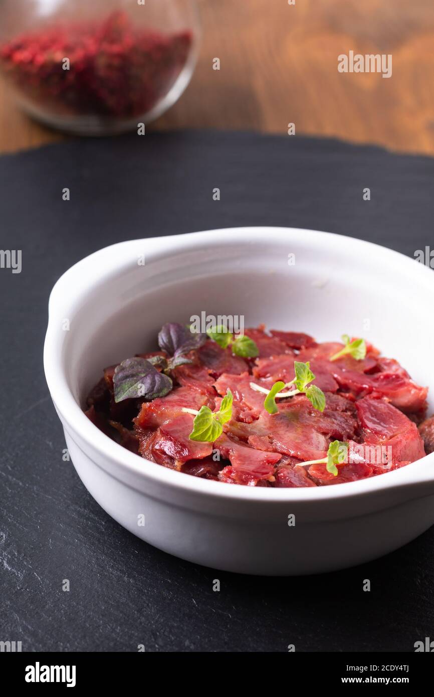 Cucina francese gesiers de poulets confits sous vide pollo gizzard Confit in tazza di ceramica bianca su tavola di ardesia nera con spazio di copia Foto Stock