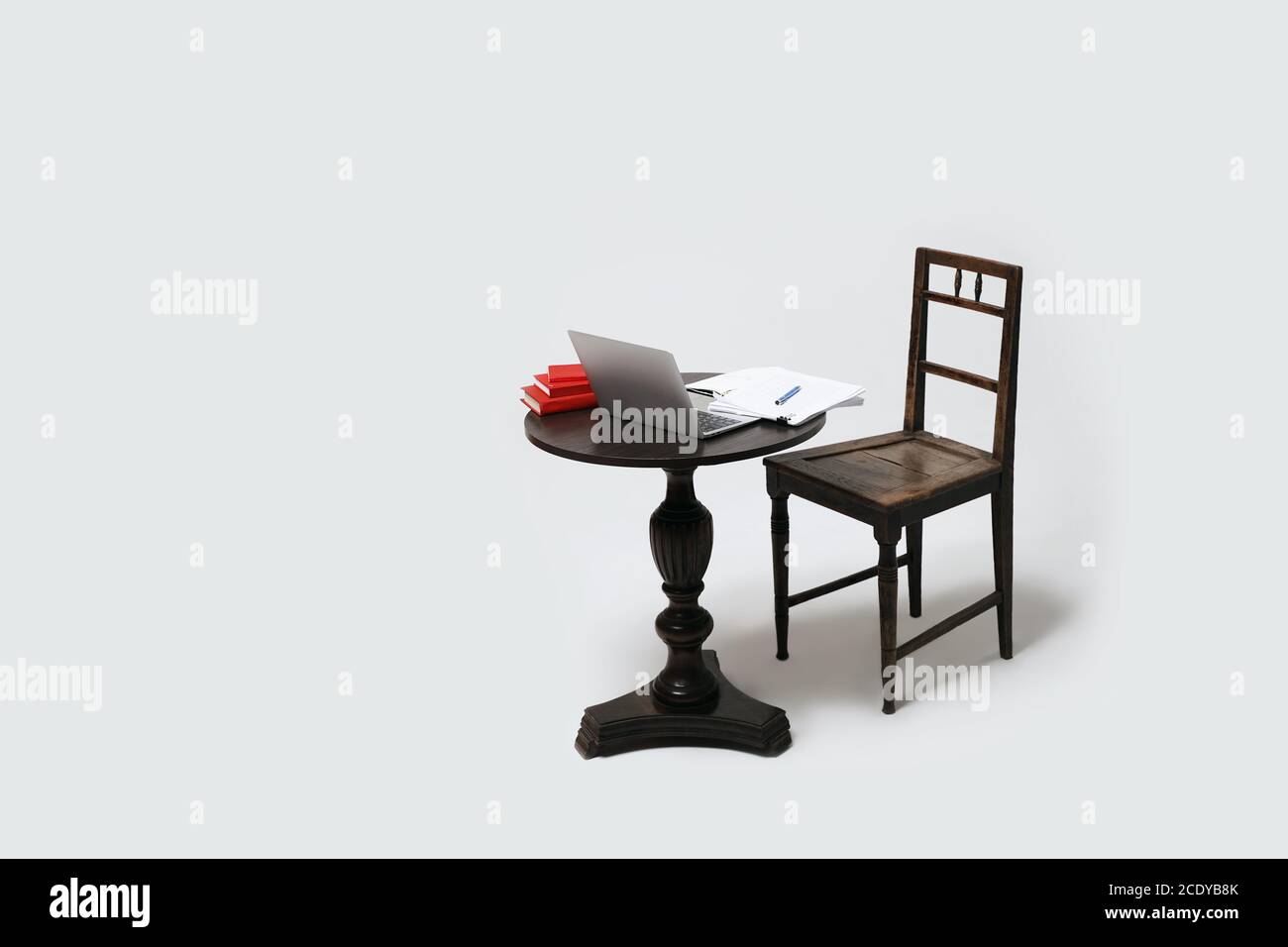 Tavolo e sedia vuoti con libri per computer portatili e note cartacee. Apprendimento a distanza o lavoro a distanza da casa. Isolato su sfondo bianco. Foto Stock