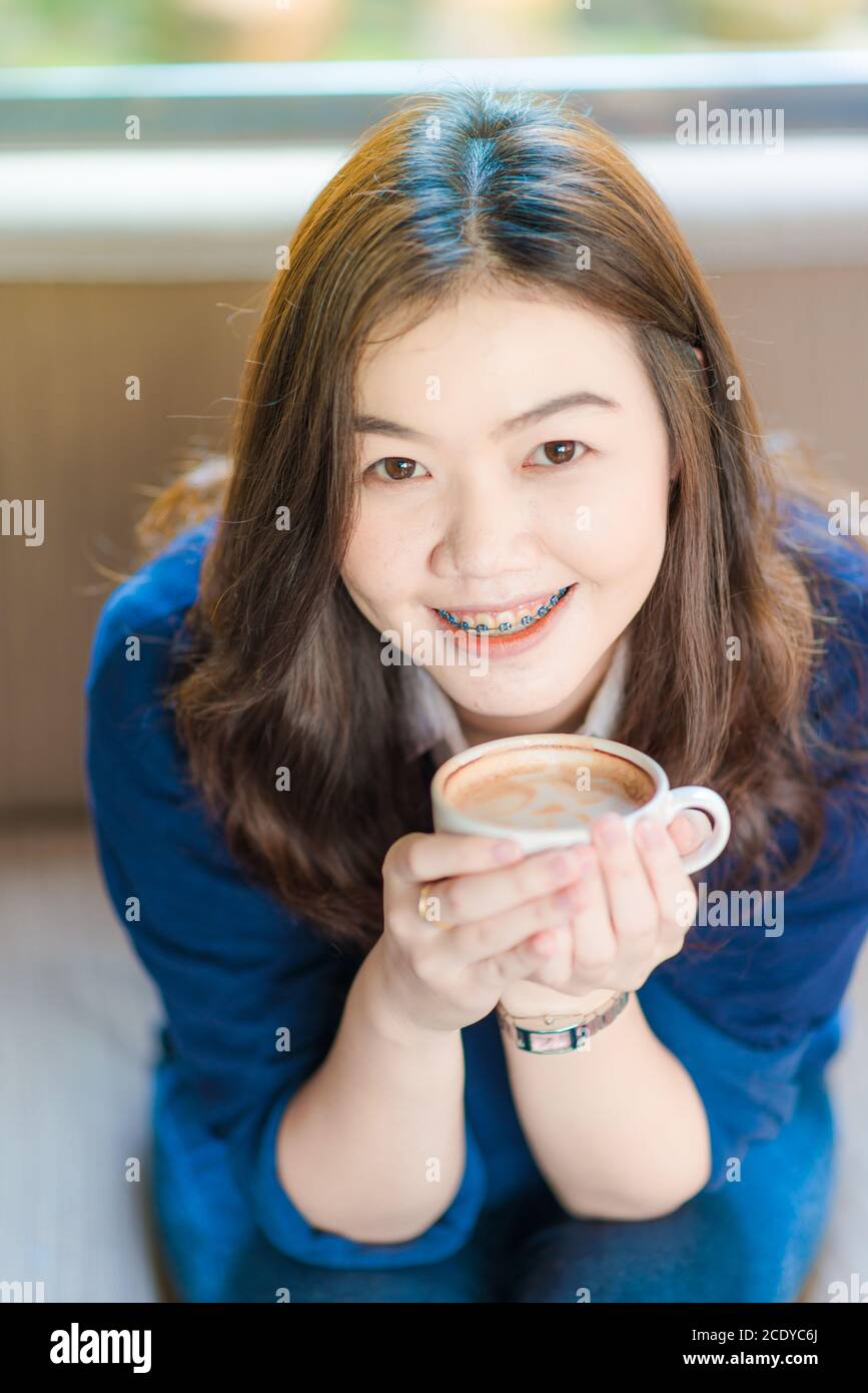 Belle donne asiatiche che bevono caffè caldo seduto sul divano vintage in caffetteria Foto Stock