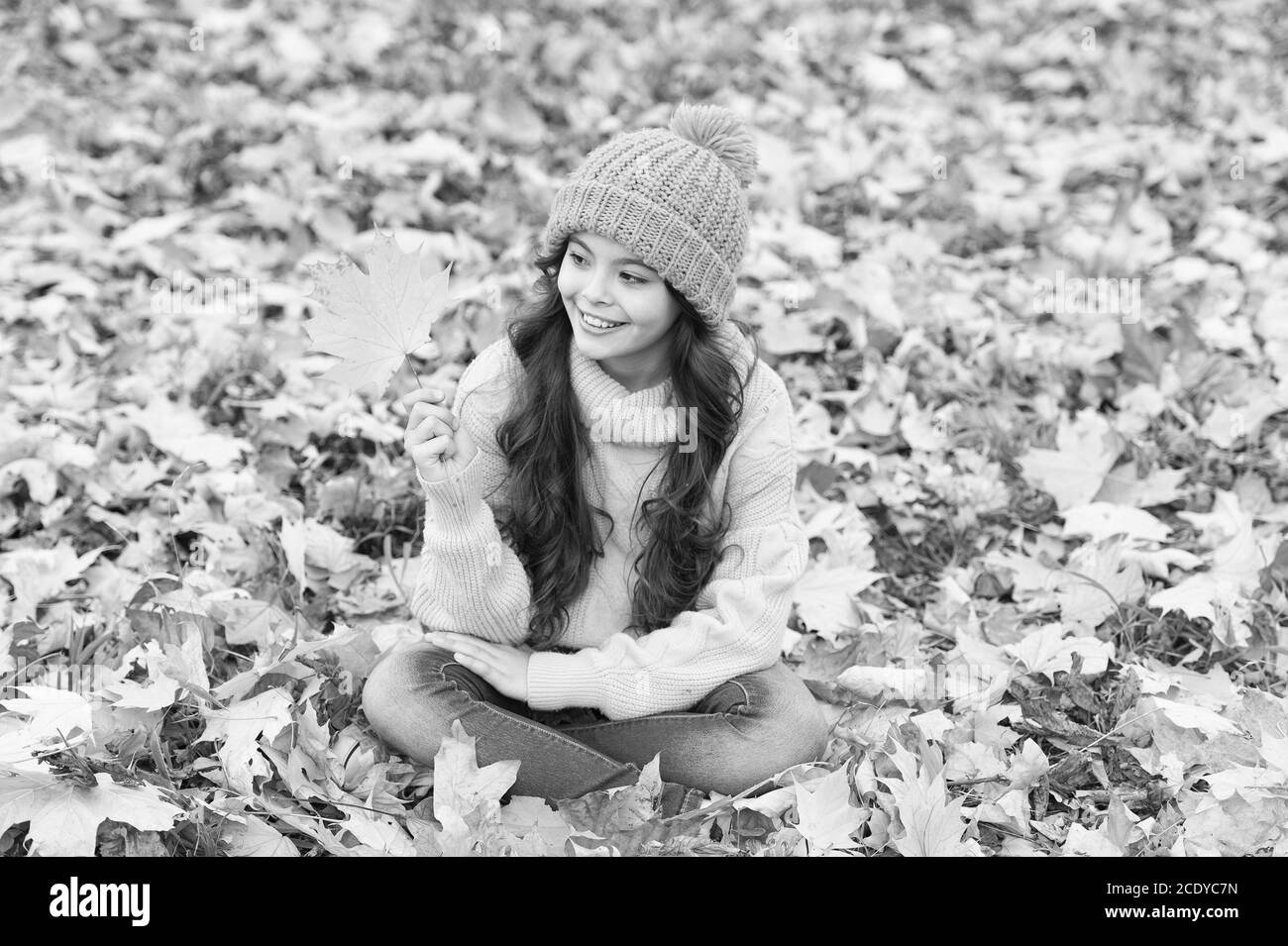 Allegro. Caldo accessorio di lana. Ragazza capelli lunghi faccia felice rientrano la natura dello sfondo. Tenervi caldi questo autunno. Il bambino nel cappello giallo all'esterno. Hat tenere in caldo. Usura del capretto morbido Caldo berretto lavorato a maglia. Foto Stock