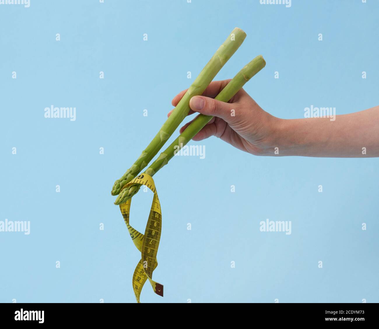 Cesoie di asparagi in una mano di donna che tiene il nastro di misurazione giallo. Foto Stock