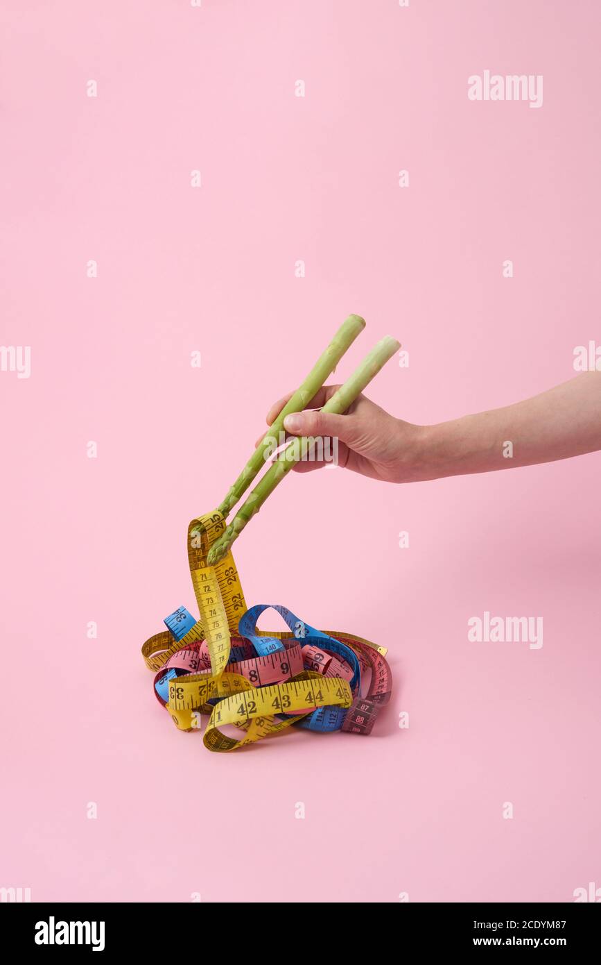 La mano della donna con bastoncini di asparagi sta prendendo dei nastri di misurazione. Foto Stock
