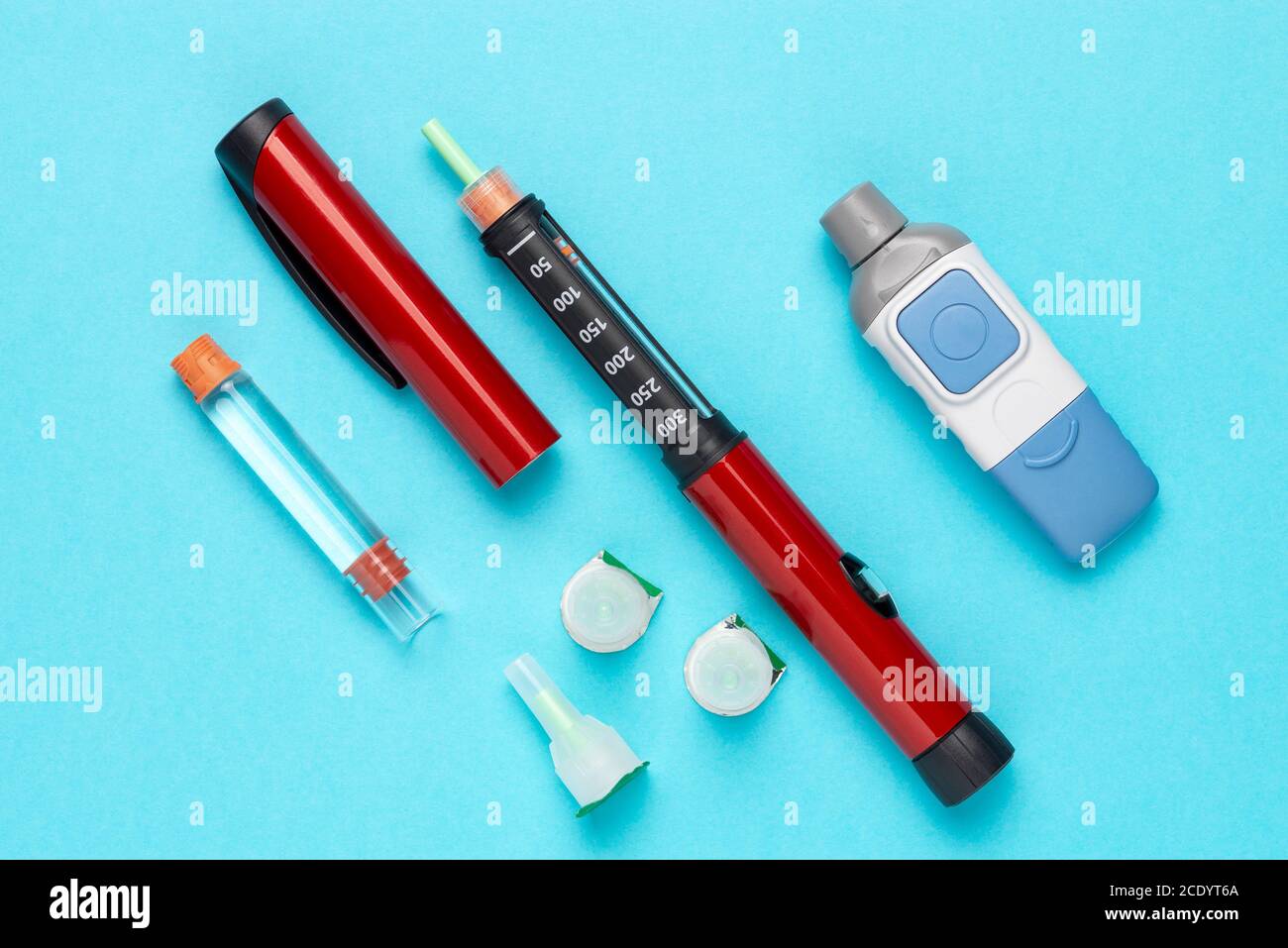 Set di lancette per diabetici con aghi di ricambio, strip, confezione di strip di ricambio, iniettore a penna, insulina di ricambio e aghi a penna su sfondo blu. Foto Stock