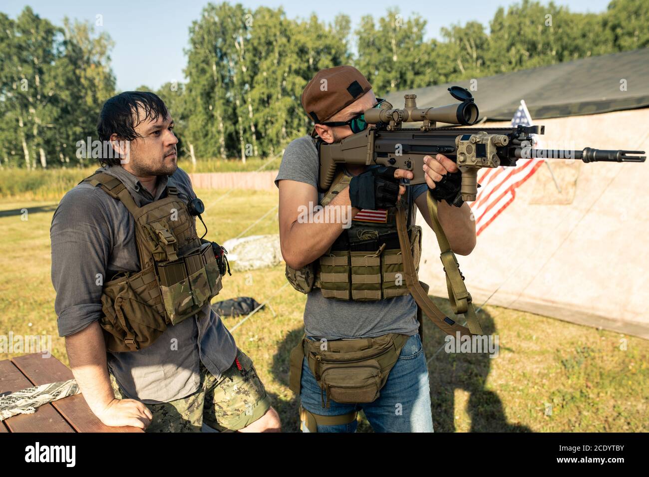 Concentrato giovane uomo in cappello utilizzando fucile mentre si pratica tiro Con pullman alla base militare americana Foto Stock