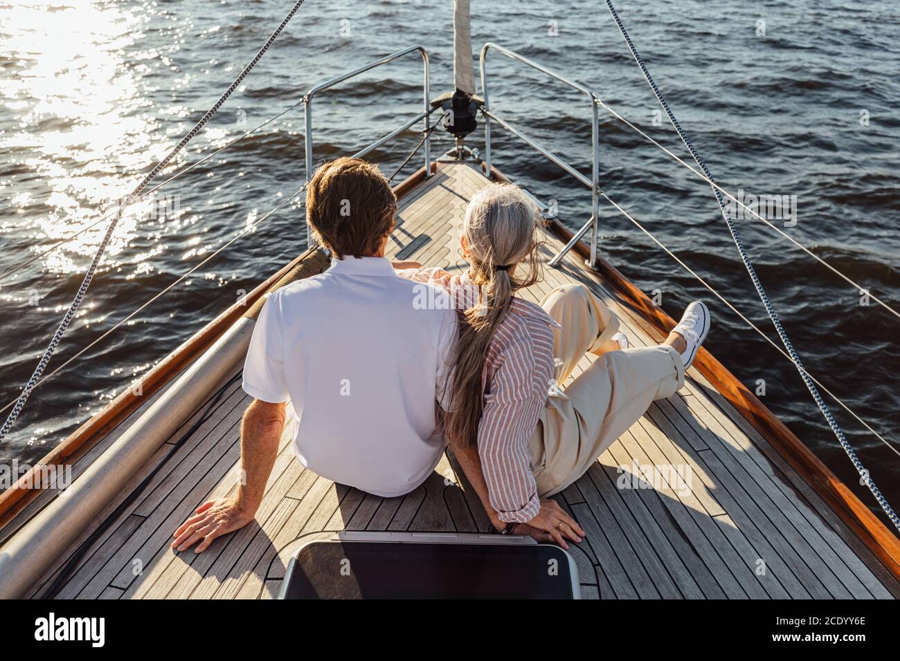 Retrovisione di due persone mature che si siedono su una prua di yacht. Una coppia anziana che ama godersi una gita in barca. Foto Stock