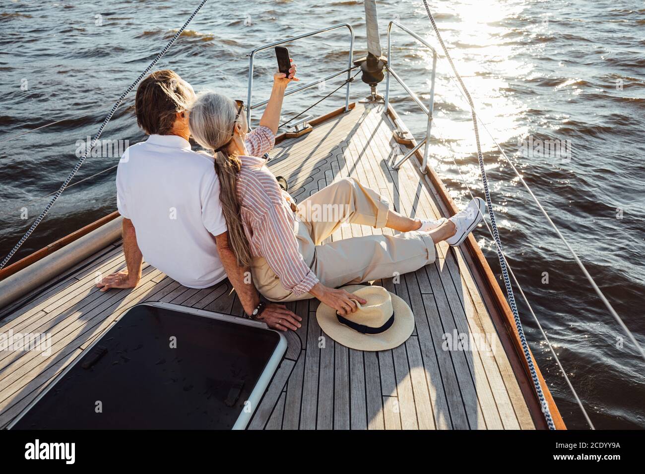 Due persone anziane seduti insieme su una prua yacht e prendendo selfie. Coppia matura che scatta fotografie sul telefono cellulare durante un viaggio in barca. Foto Stock