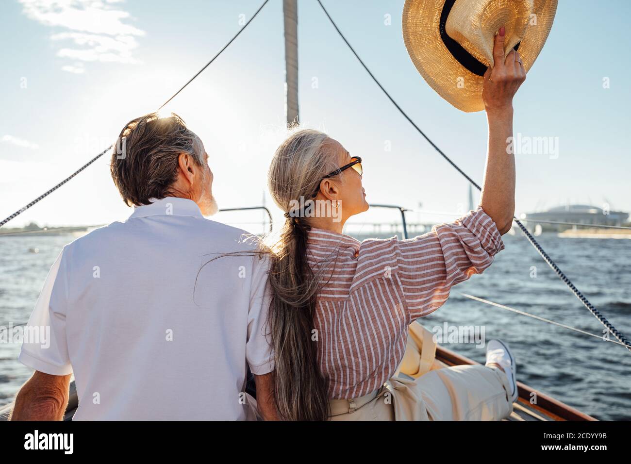 Vista sul retro di una coppia matura rilassata seduto sullo yacht. Cappello da donna elegante durante il viaggio in barca. Foto Stock