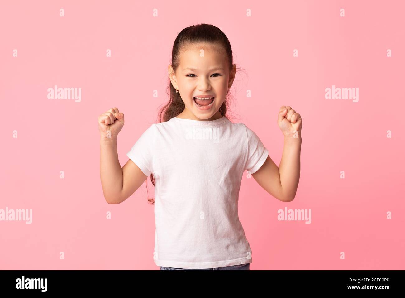 Bambina asiatica scuotendo pugni, facendo gesto vincitore Foto Stock
