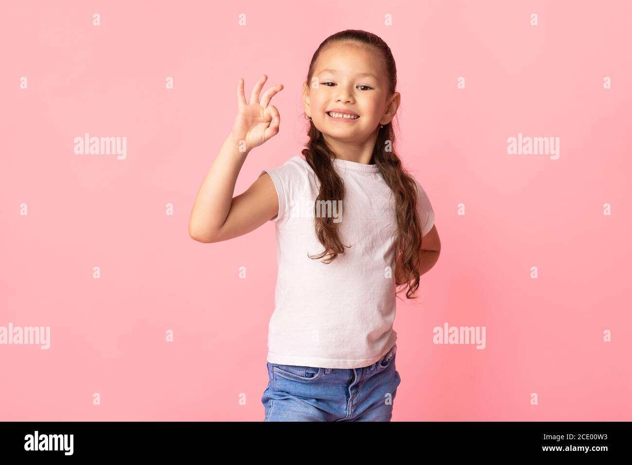 Ragazza asiatica che mostra un gesto ok e sorridente Foto Stock