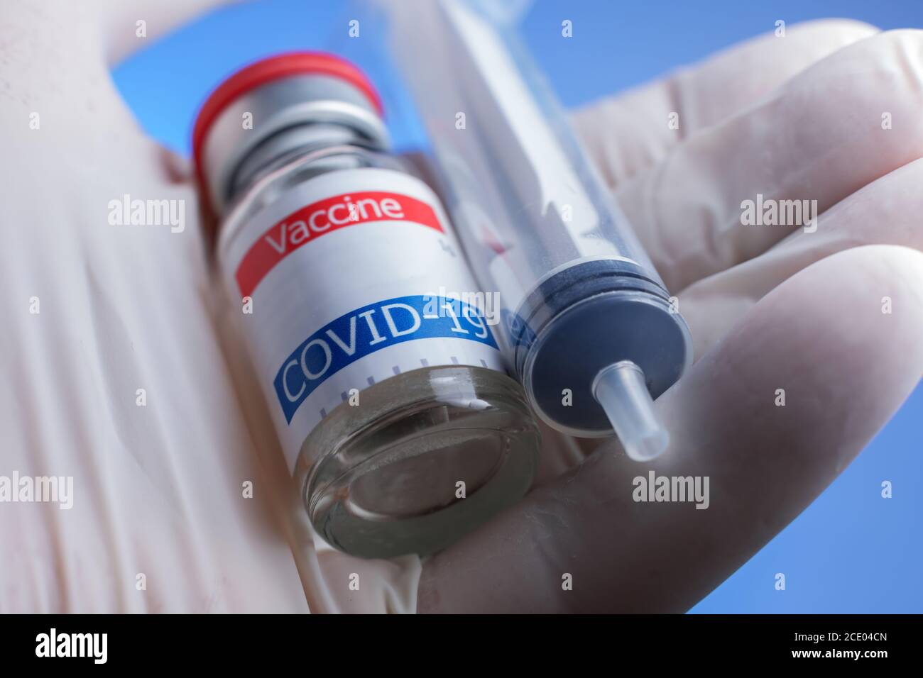 primo piano del flaconcino di vaccino coronavirus con supporto a mano e siringa Foto Stock