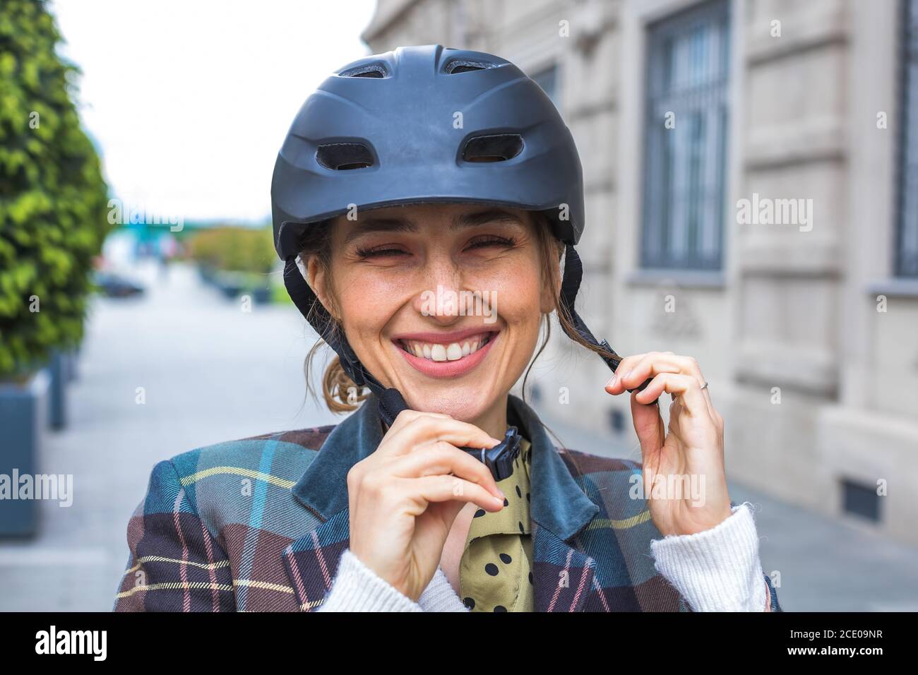 ritratto di giovane donna che mette casco di protezione bicicletta Foto Stock