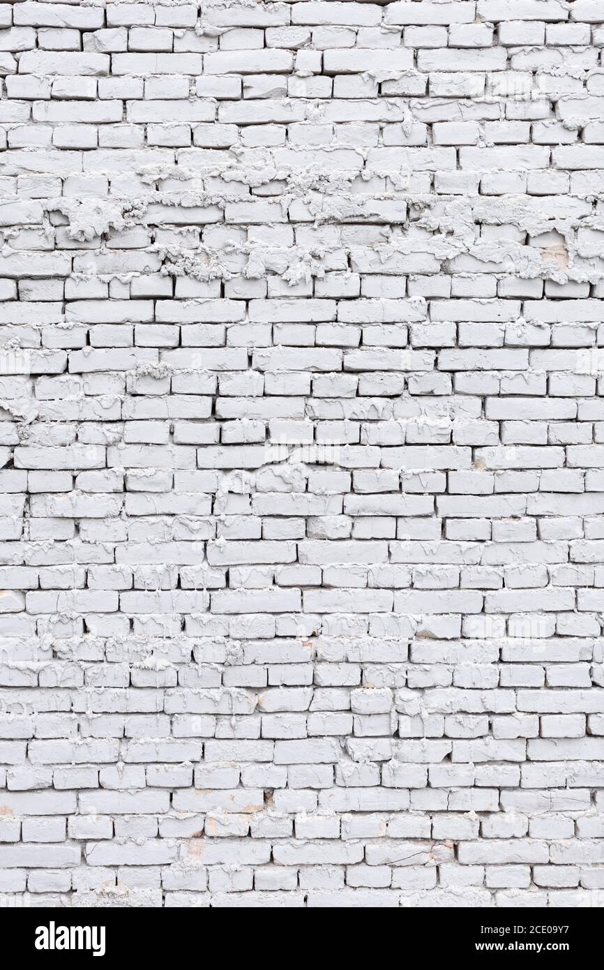 parete di mattone bianca ruvida con fondo di gesso che perde Foto Stock