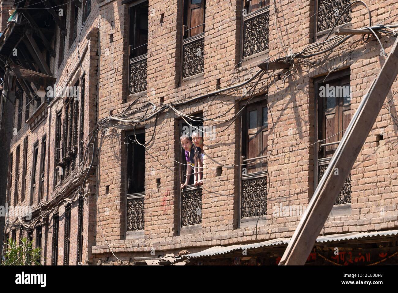 Bhaktapur/Nepal-19.03.2019:Yong ragazze che guardano attraverso la finestra Foto Stock