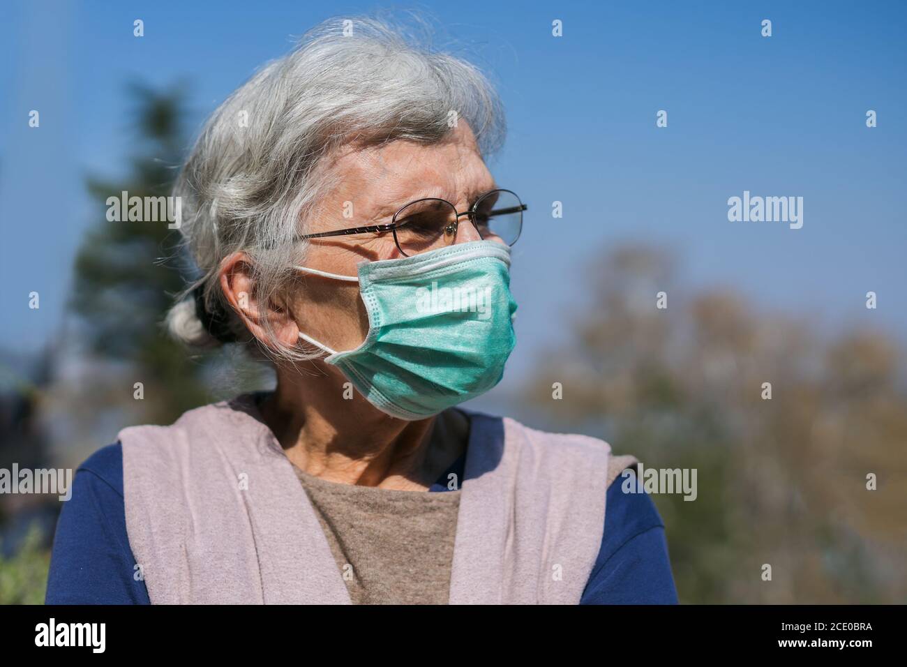 donna anziana con maschera facciale in piedi sulla terrazza Foto Stock