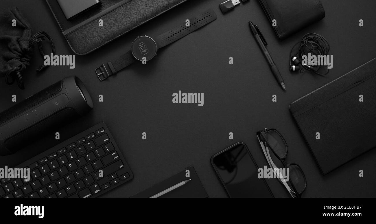 Concetto aziendale. Composizione piatta con vari gadget neri su superficie nera scura Foto Stock