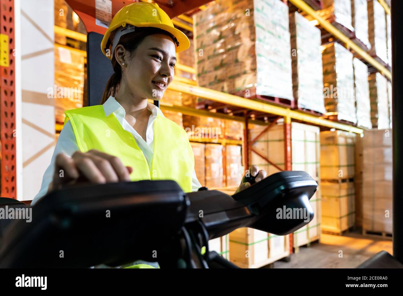 Lavoratore magazzino asiatico con carrello elevatore in magazzino Foto Stock