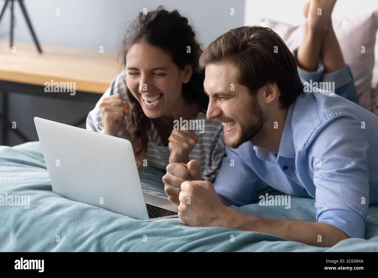 La giovane coppia si è sopravdata a letto, guardando lo schermo del computer portatile. Foto Stock