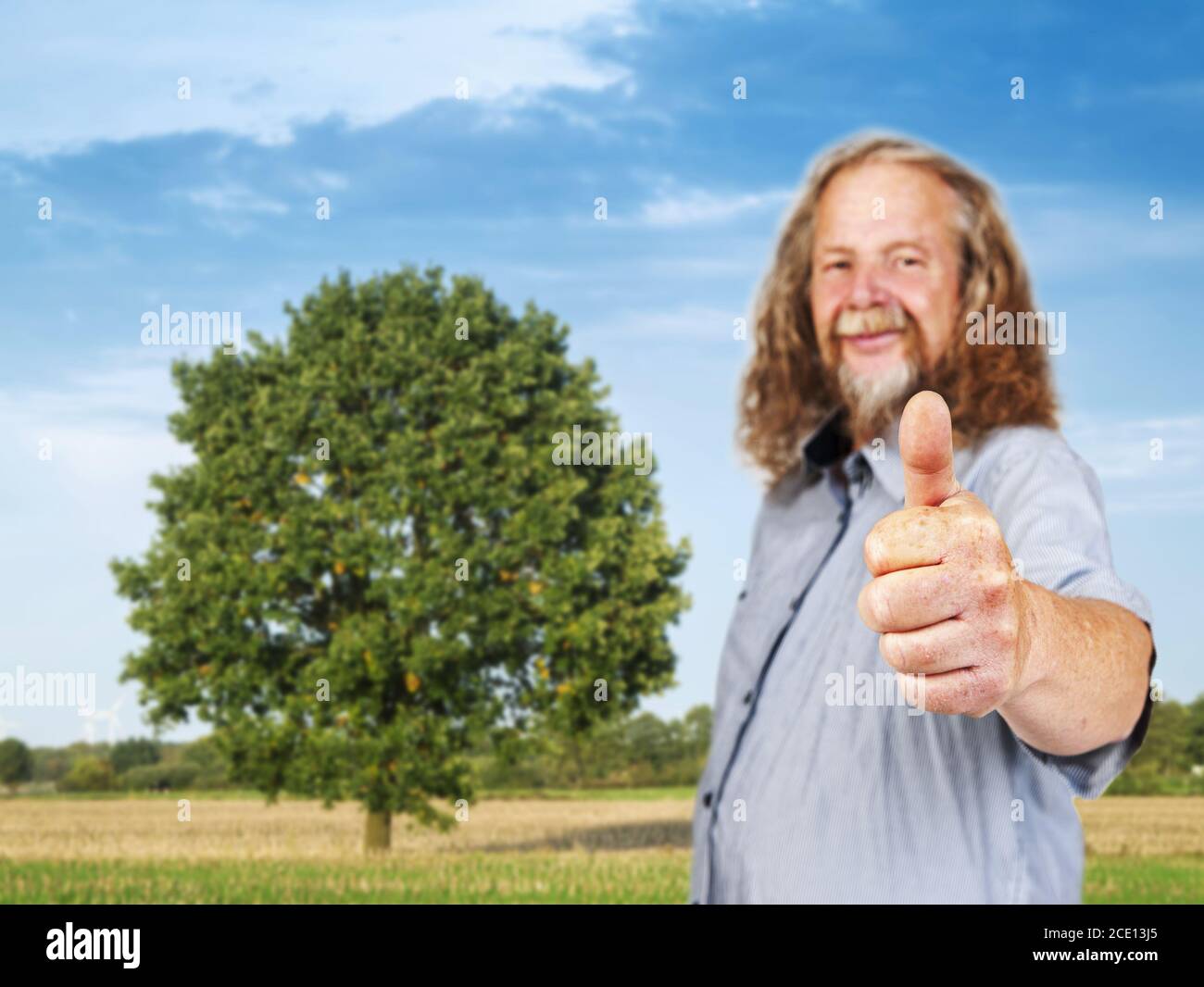 L'uomo anziano mostra i pollici sul campo Foto Stock