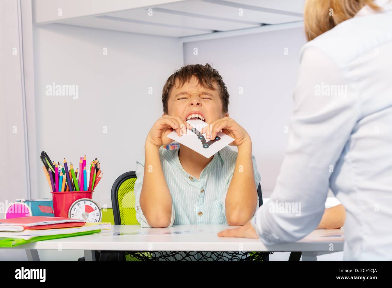 Tessera autistica per bambini che esprime emozioni negative, lanciando tantrums mentre si imparano i numeri seduti dall'insegnante durante la terapia ABA Foto Stock