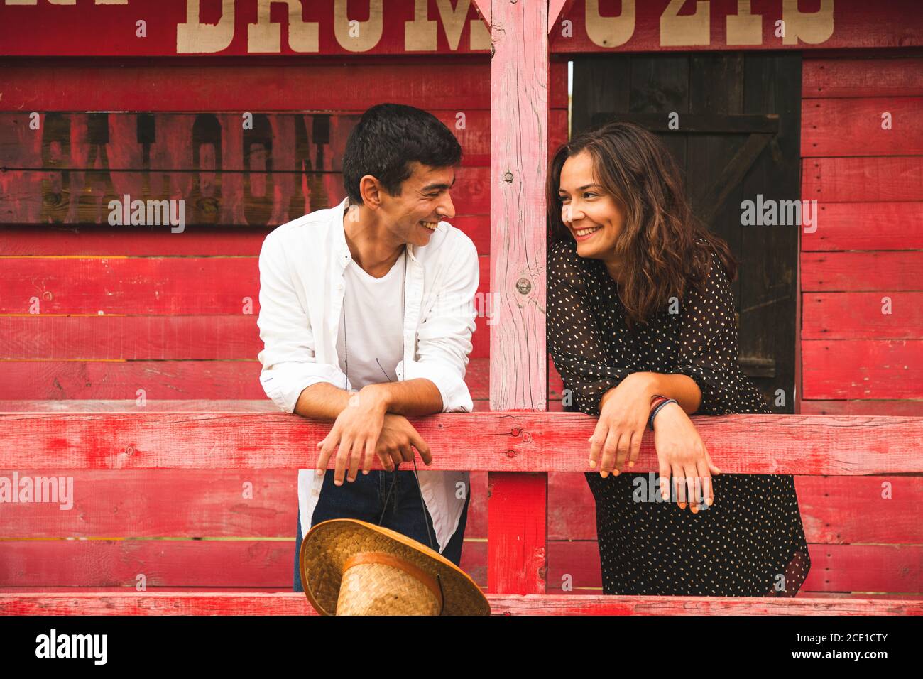 Bella coppia Flirtare e sorridere fuori di un Red Wooden Saloon. Ranch Concept Photography Foto Stock
