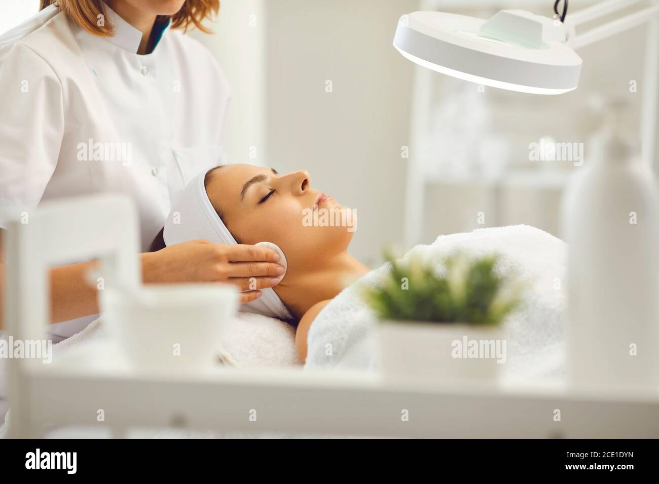 Cosmetologo pulizia viso donna con tamponi in cotone in salone di bellezza Foto Stock