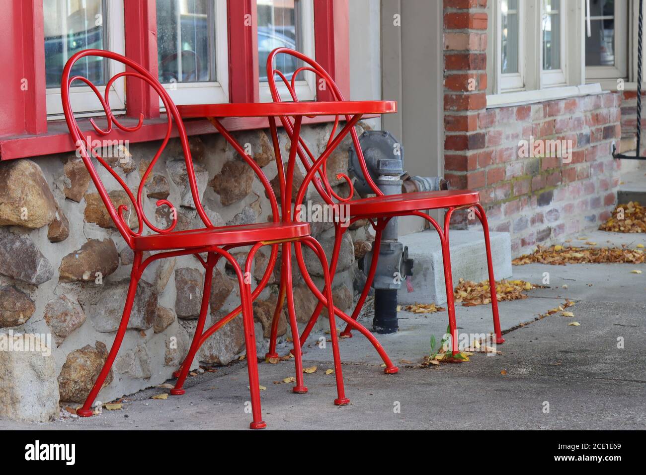 I mobili in ferro battuto rosso si trovano all'esterno della caffetteria. Foto Stock