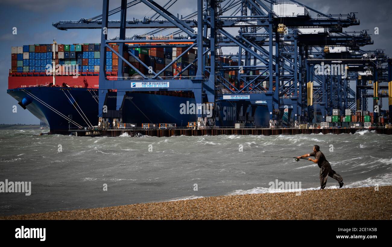 Beach Fishing tempesta tempo - un pescatore calata durante il tempo tempestoso vicino al porto di Felixstowe UK. Pesca in spiaggia Regno Unito. Foto Stock