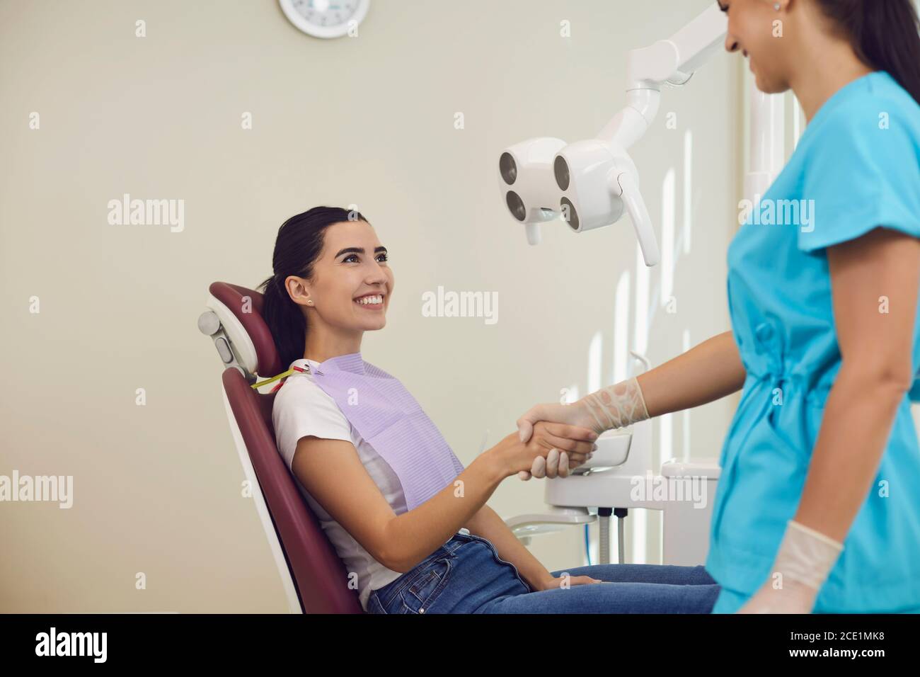 Donna sorridente paziente scuotendo la mano al dentista dopo il dente riuscito esame in clinica odontoiatrica Foto Stock