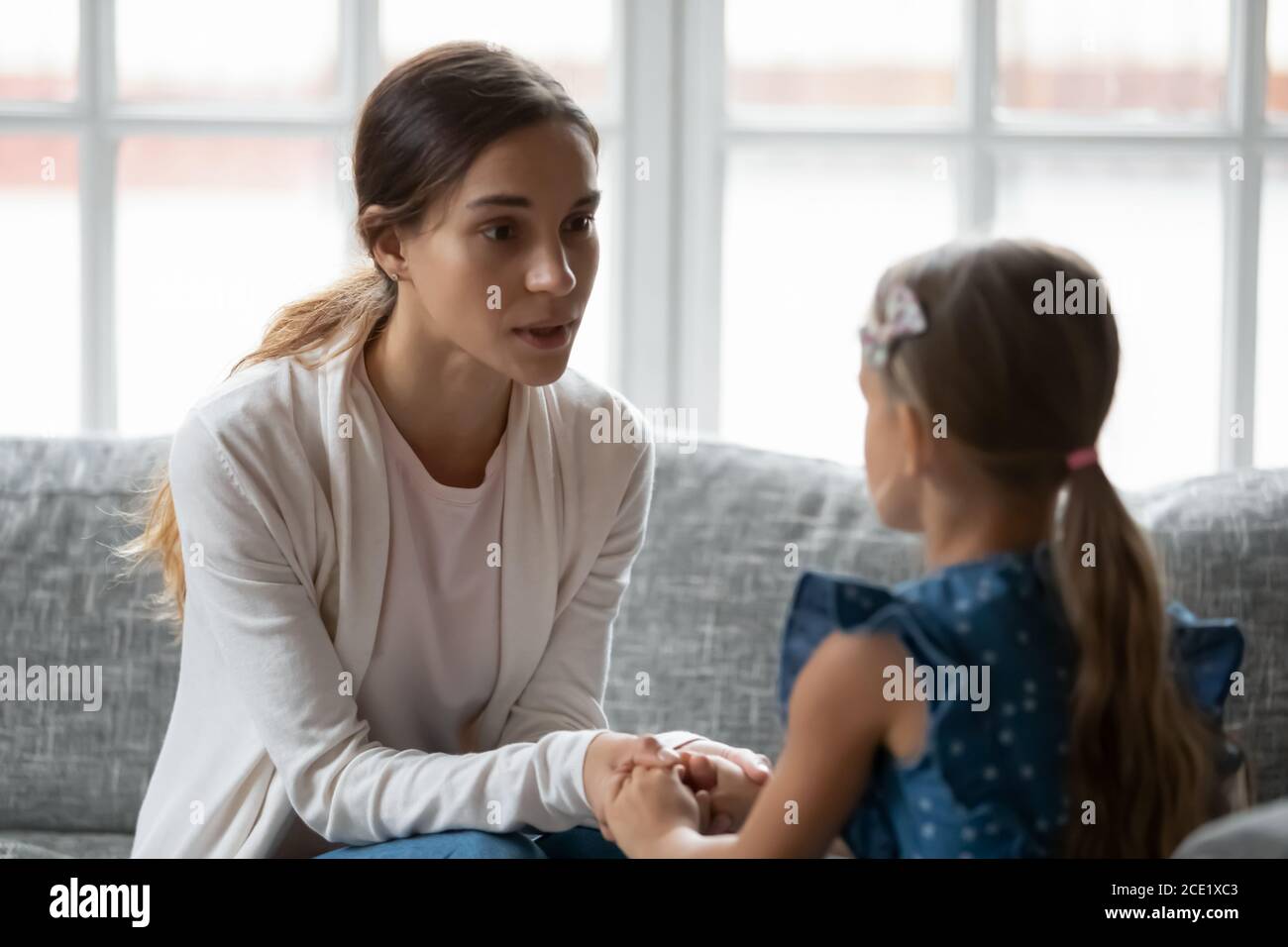 Preoccupata giovane mamma che sostiene, dando consigli alla piccola figlia. Foto Stock
