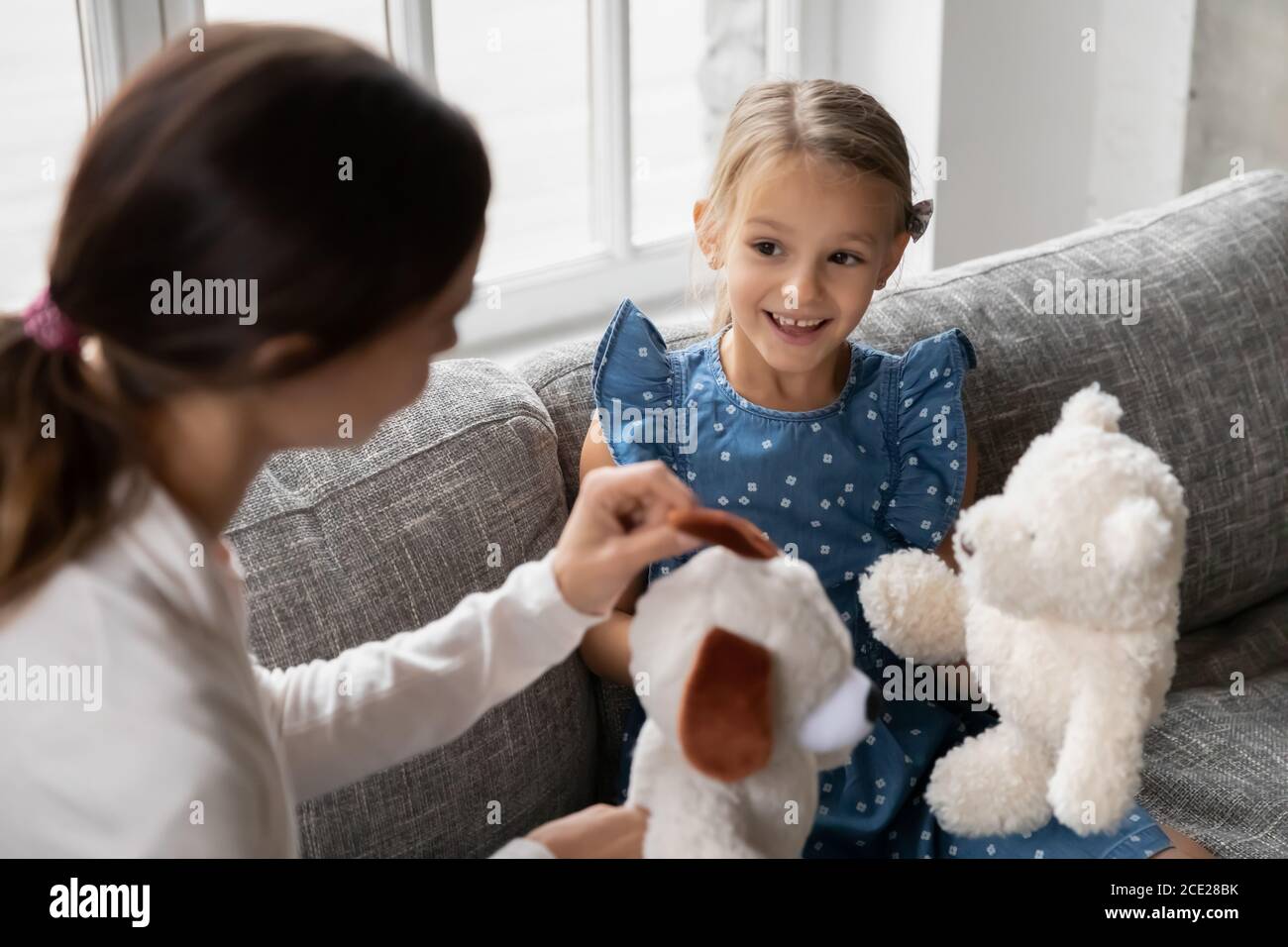 Interessato piccolo capretto cute che gioca i giocattoli con la madre giovane. Foto Stock
