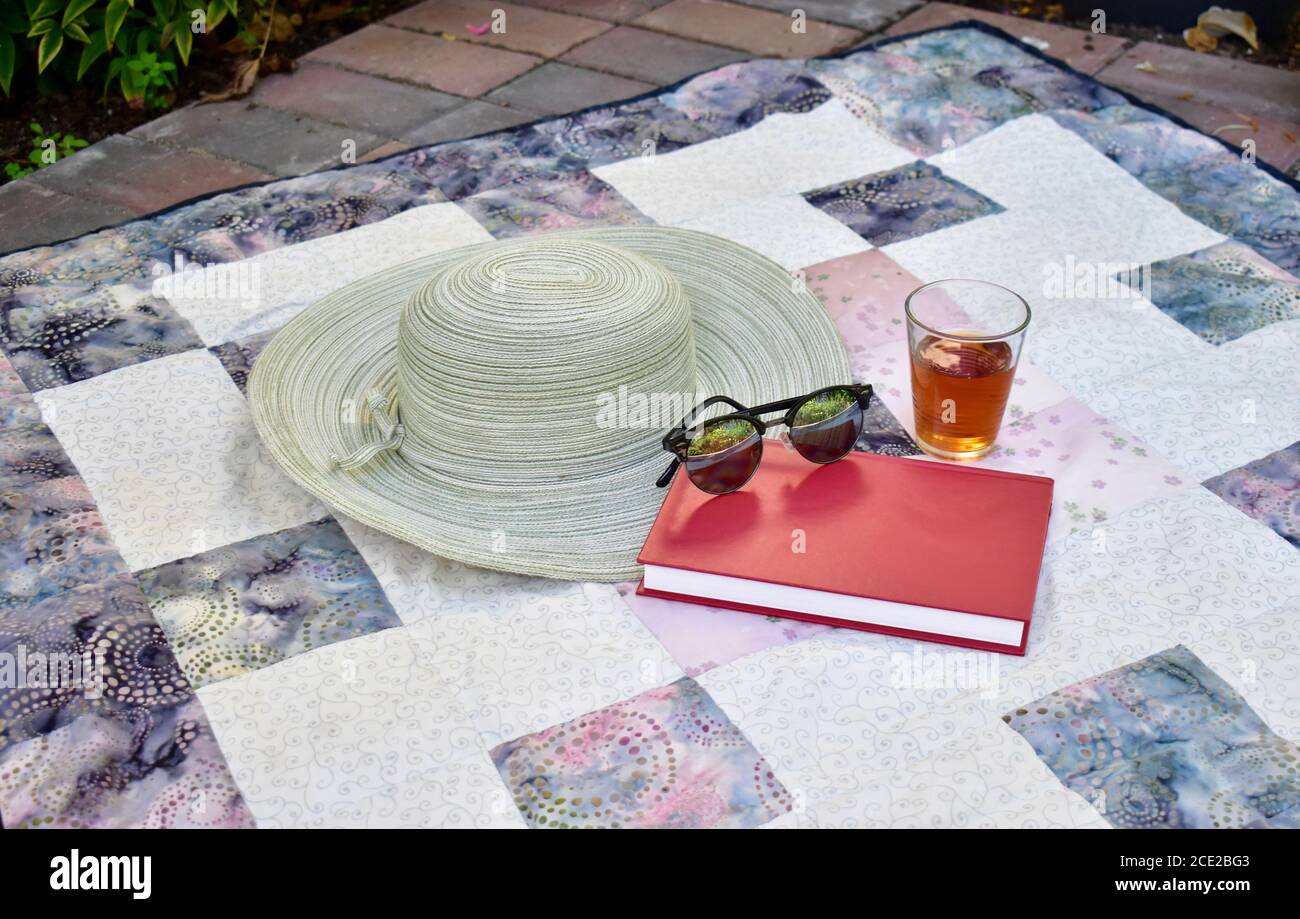 Giardino esterno per una rilassante stagione estiva lettura pomeridiana con bevande fresche e un ampio cappello in vacanza a casa Foto Stock