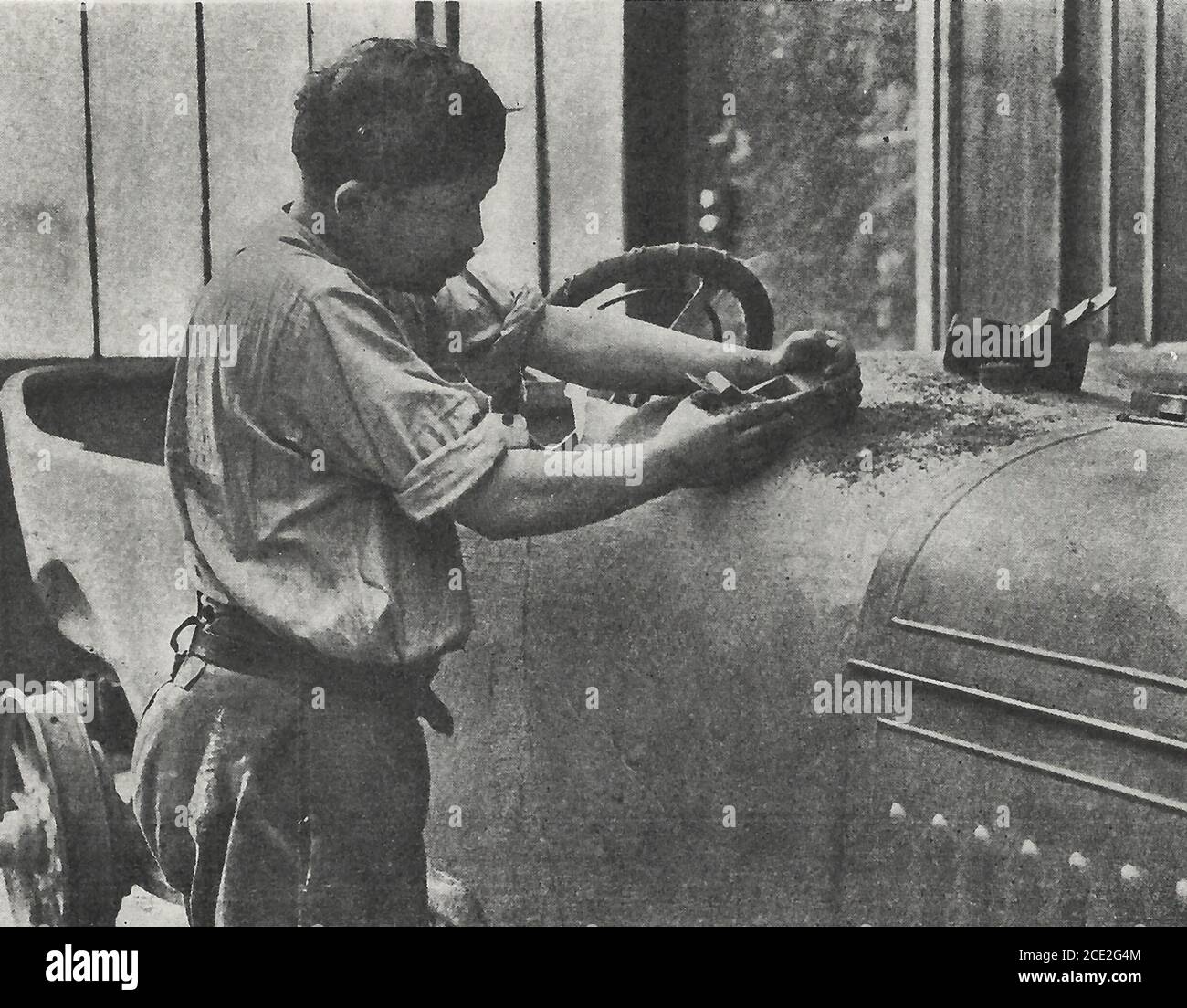 Levigare la carrozzeria dell'auto con un piano prima di applicare vernice e lucidatura - fabbricazione di un'automobile, 1914 Foto Stock