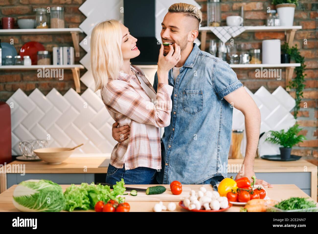 Bella coppia Giovane è di alimentare ciascun altro e sorridente durante la cottura in cucina a casa Foto Stock