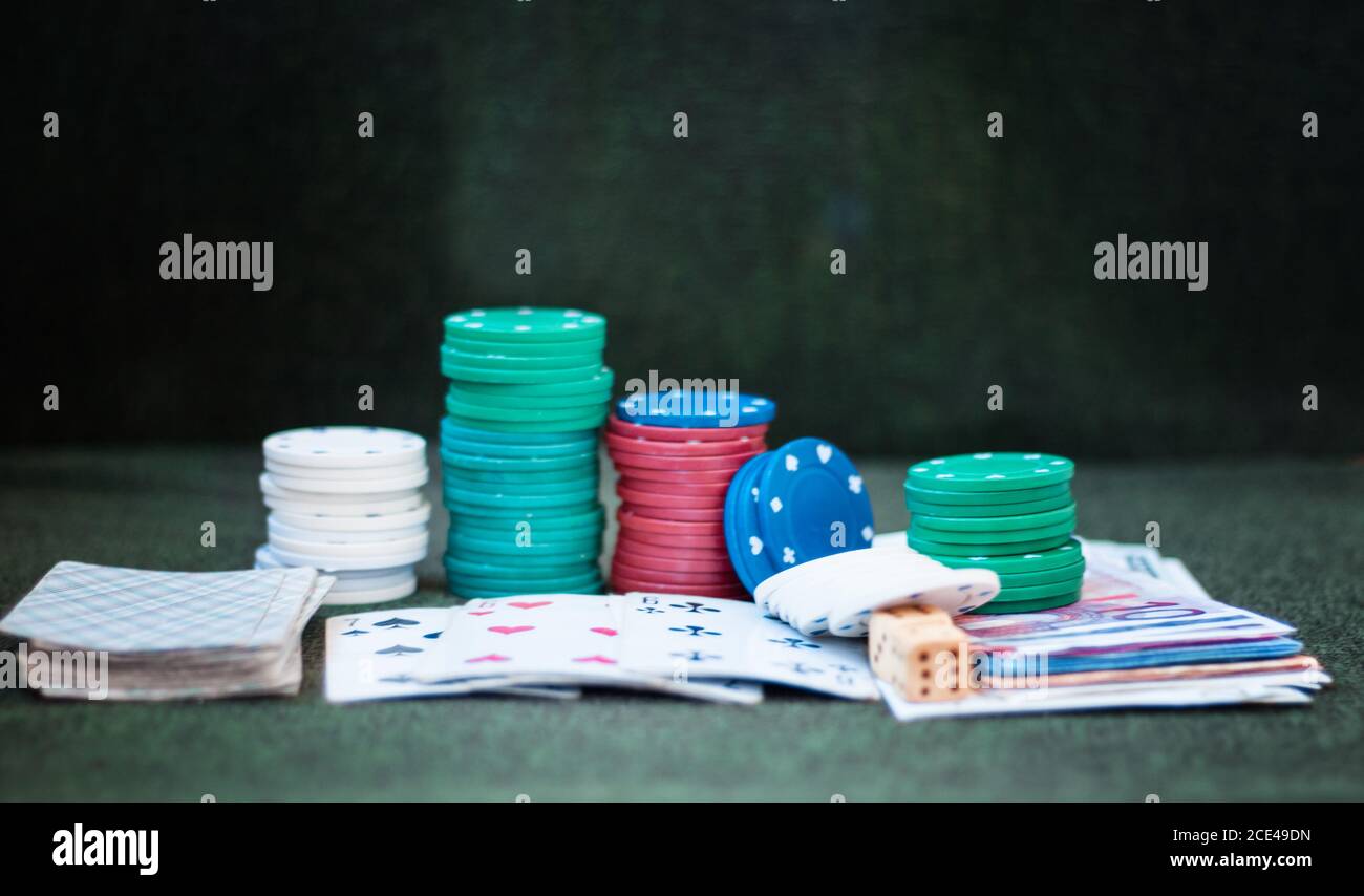 I chip del poker del casinò si accatastano con le carte da gioco, i dadi e i soldi su sfondo verde feltro Foto Stock