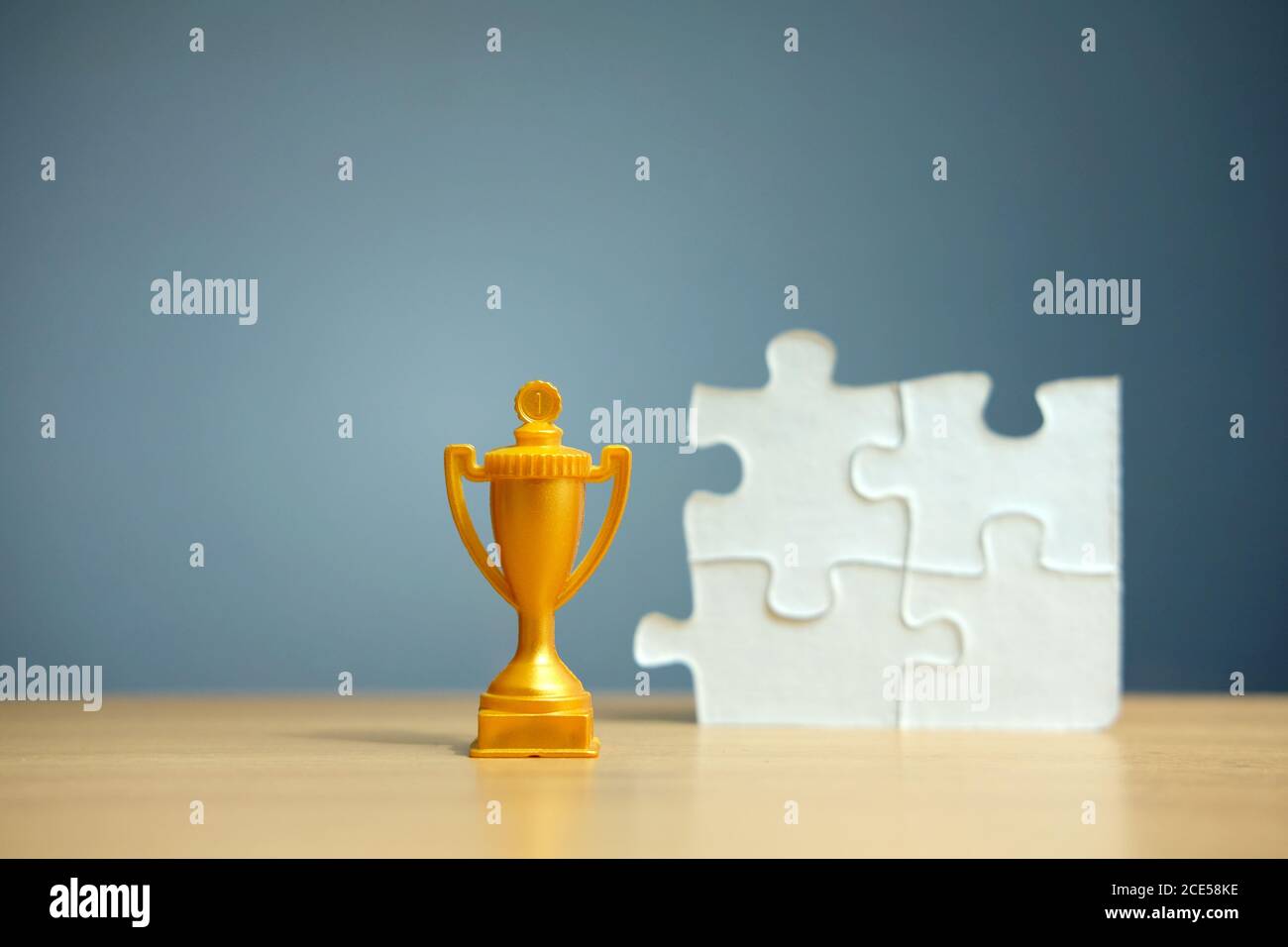 Trofeo d'oro con puzzle bianco su un tavolo di legno Foto Stock