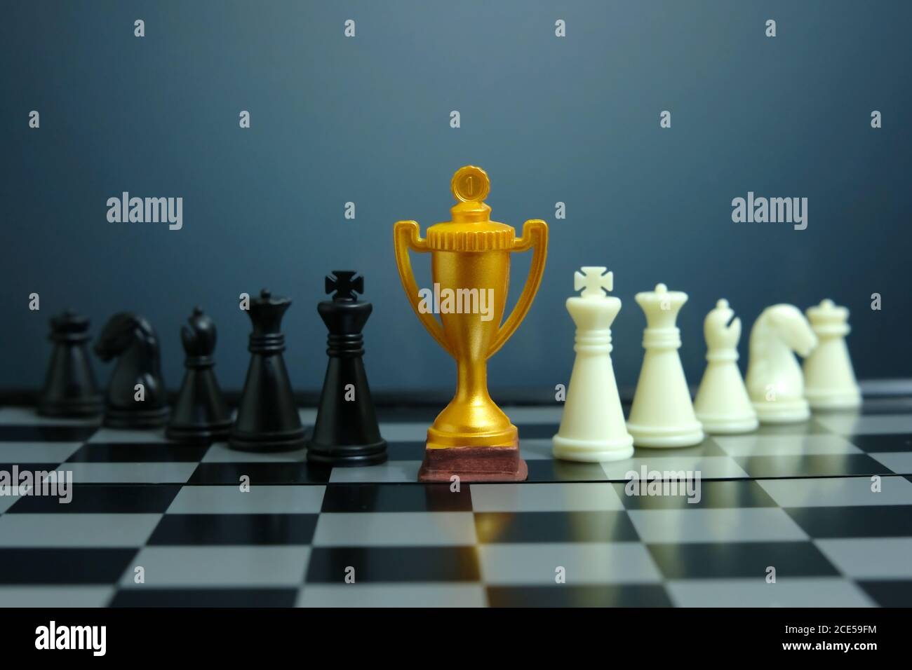 Foto concettuale della strategia aziendale – trofeo d'oro in piedi sulla scacchiera con pedina di scacchi Foto Stock