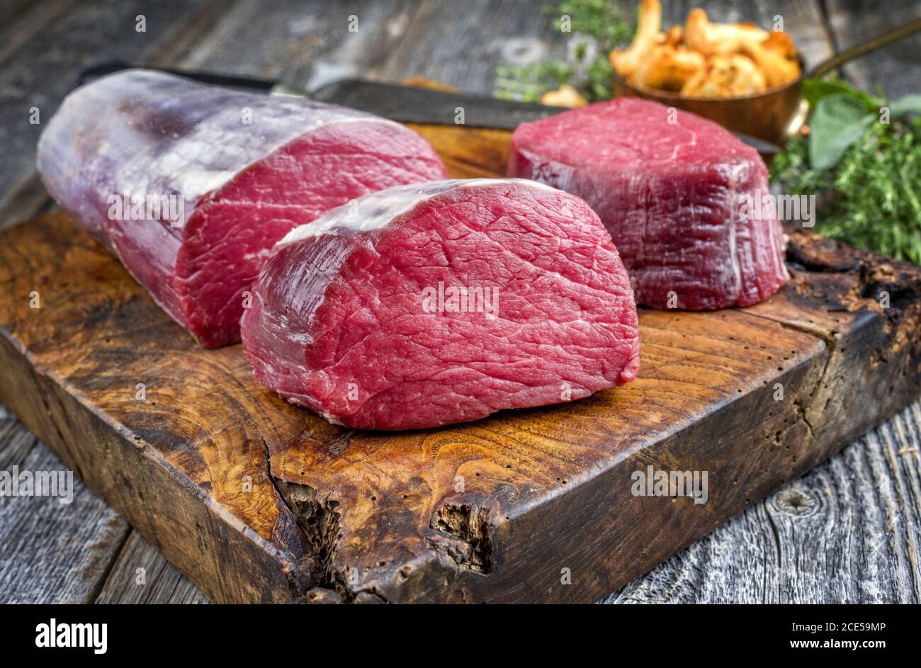 Bistecca di filetto di manzo stagionato, naturale come primo piano con i chanterelles su un tagliere di legno Foto Stock
