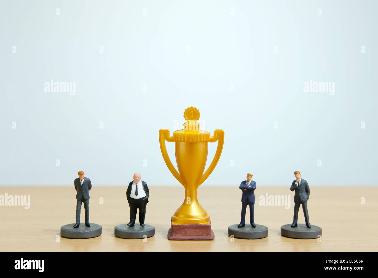Concetto di business in miniatura - riga di business uomo d'affari con trofeo d'oro al centro Foto Stock