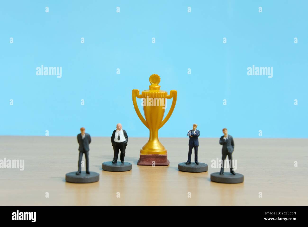 Concetto di business in miniatura - riga di business uomo d'affari con trofeo d'oro al centro Foto Stock