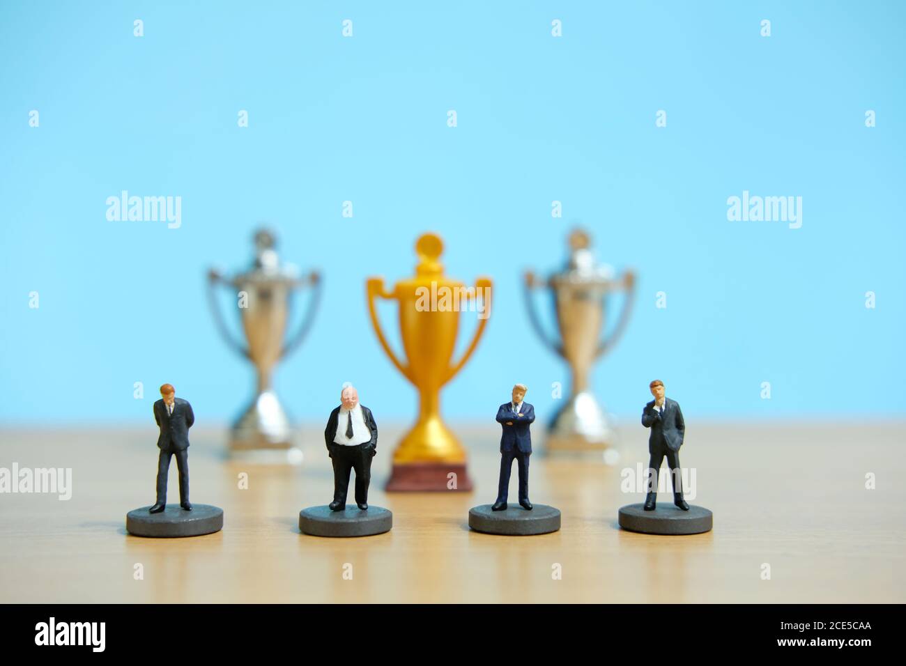 Concetto di business in miniatura - riga di business uomo d'affari con trofeo d'oro al centro Foto Stock