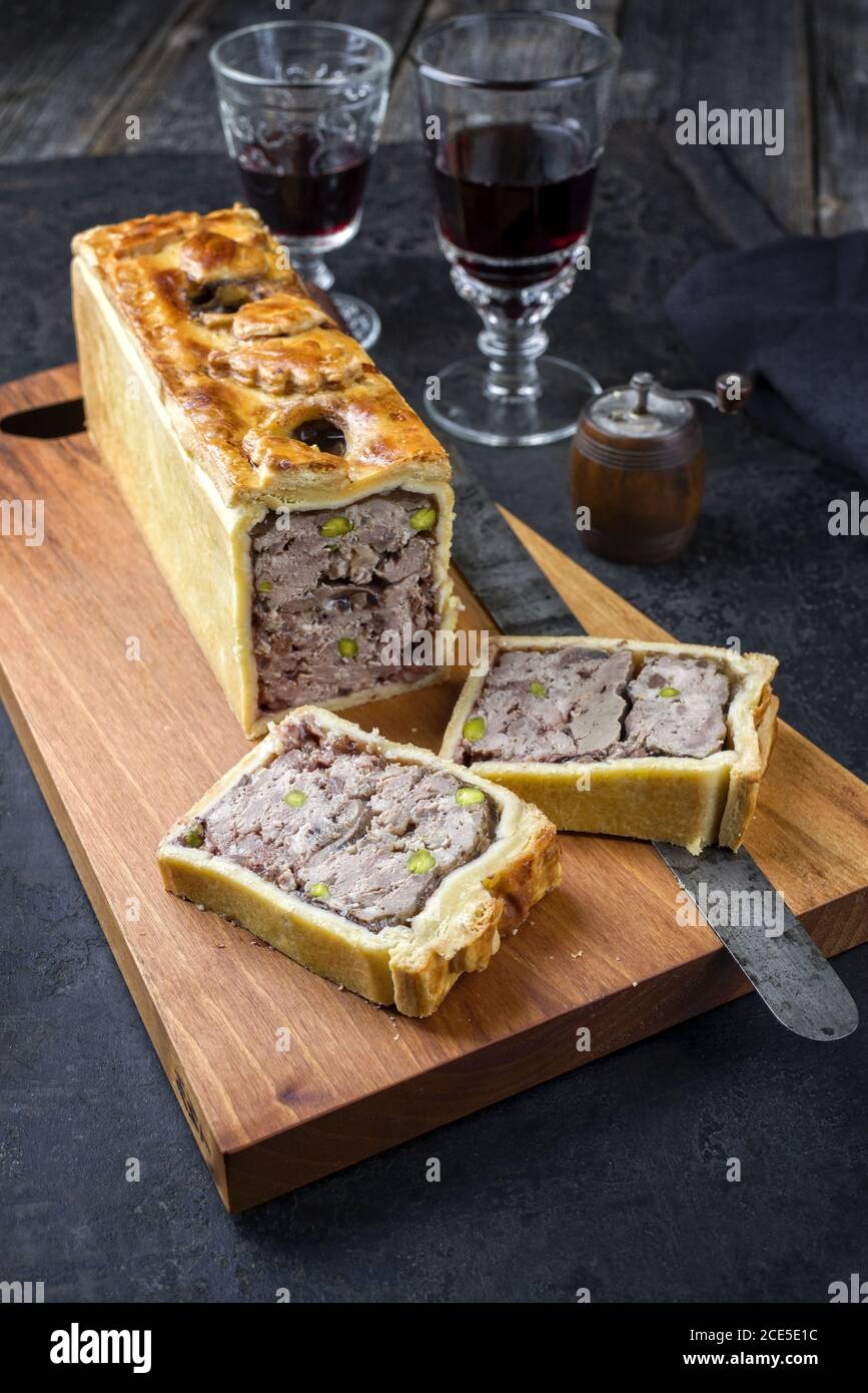 Tradizionale francese Pate en croute con carne d'oca e fegato come primo piano con vino rosso su un legno di design moderno scheda Foto Stock