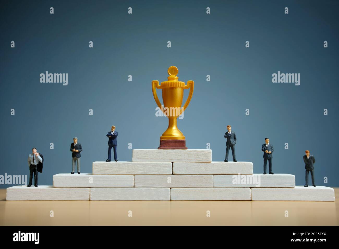 Foto concettuale strategia aziendale - miniatura di uomo d'affari si leva su scala podio con trofeo d'oro Foto Stock
