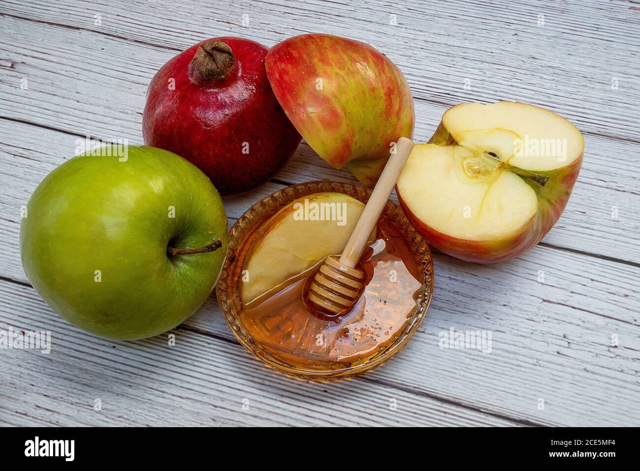 Prodotti tradizionali per la celebrazione del Rosh Hashanah - mele, melograno, miele, favi - su sfondo bianco di legno Foto Stock
