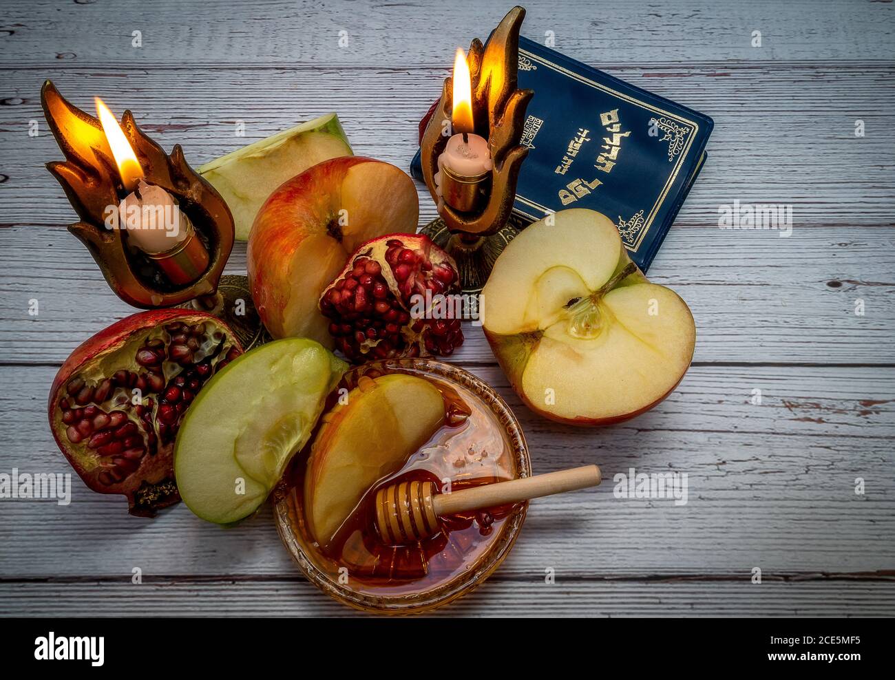 Prodotti tradizionali per la celebrazione del Rosh Hashanah - mele, melograno, miele, favi - su sfondo bianco di legno Foto Stock