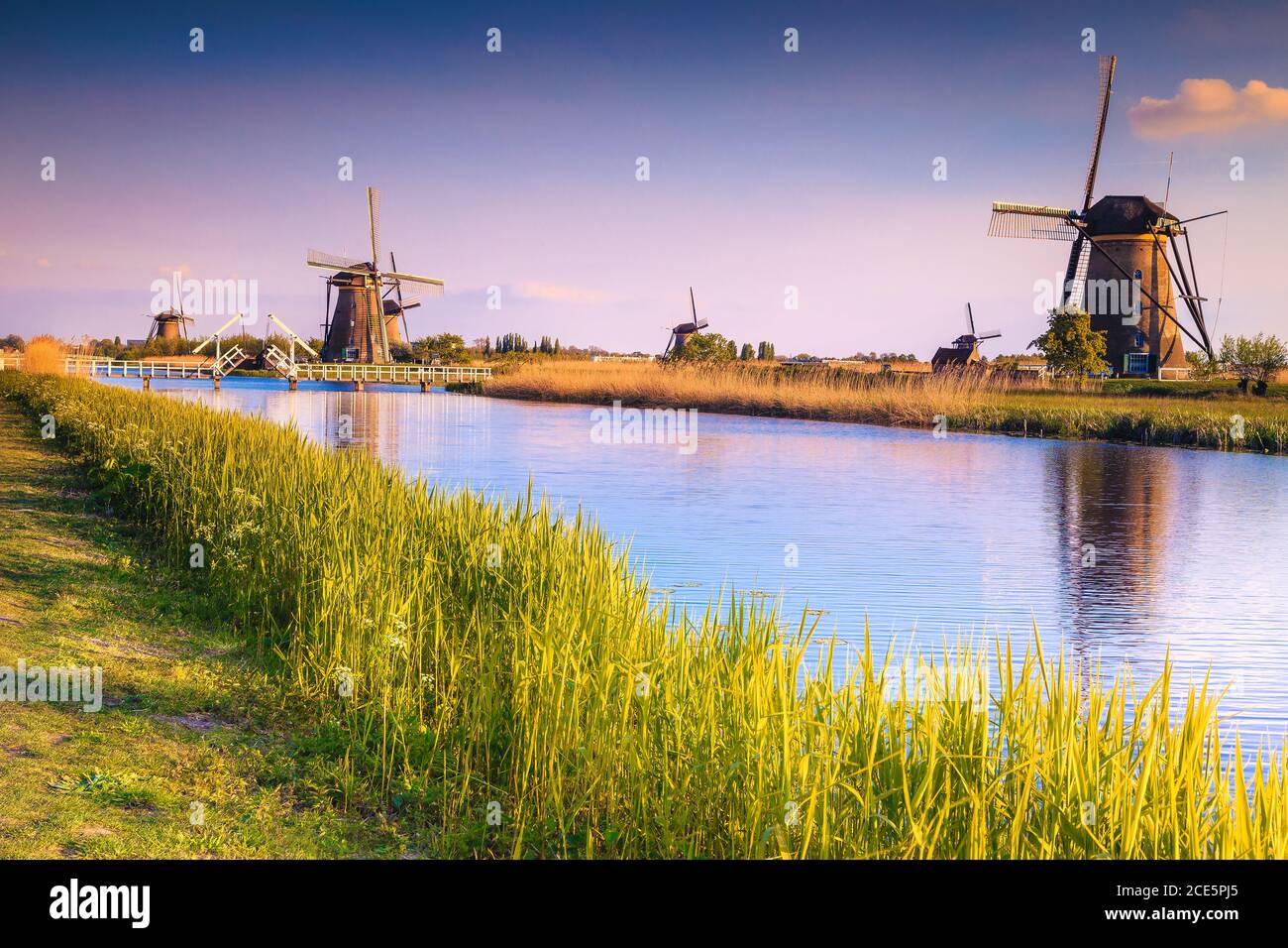 Mulini a vento tradizionali olandesi rustici sulle rive dei canali d'acqua nel museo Kinderdijk, patrimonio dell'umanità dell'UNESCO, Paesi Bassi, Europa Foto Stock