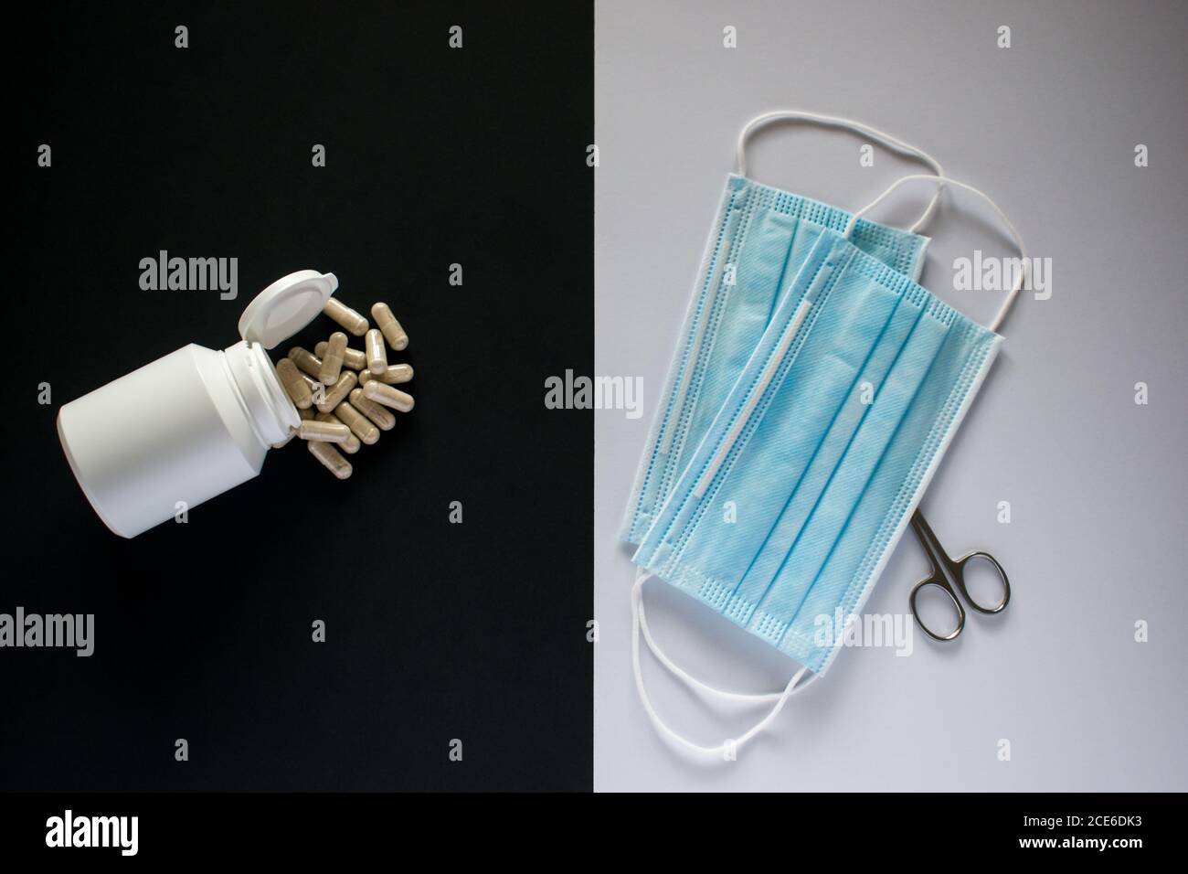 Pillole mediche di fronte maschera medica con forbici su nero e. sfondo bianco Foto Stock
