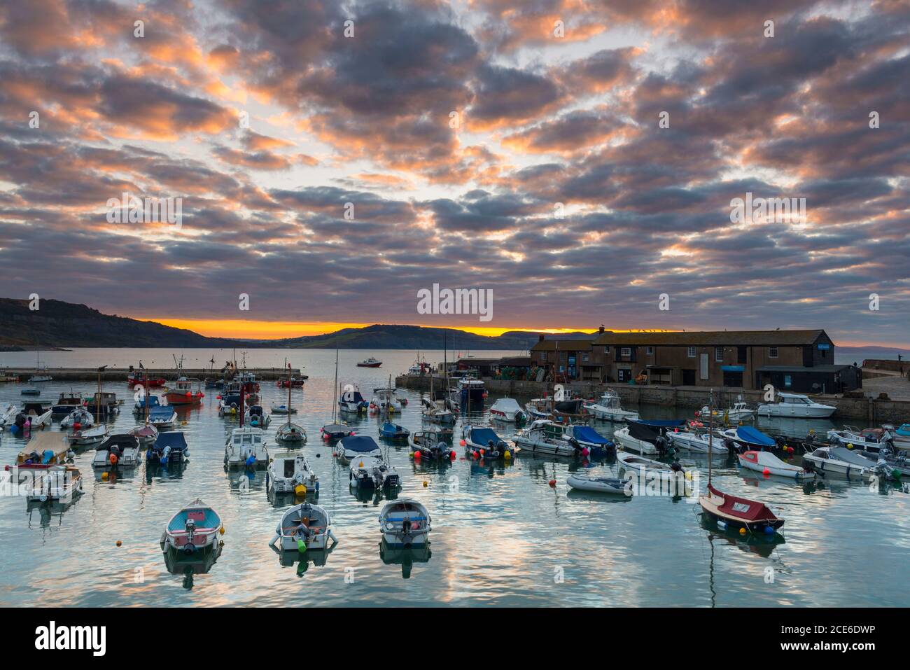 Lyme Regis, Dorset, Regno Unito. 31 agosto 2020. Regno Unito Meteo. Le nubi sopra il porto di Cobb illuminano l'arancione all'alba a Lyme Regis in Dorset il lunedì di festa della Banca. Picture Credit: Graham Hunt/Alamy Live News Foto Stock